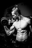 Svalnatý muž při posilování ve fitness